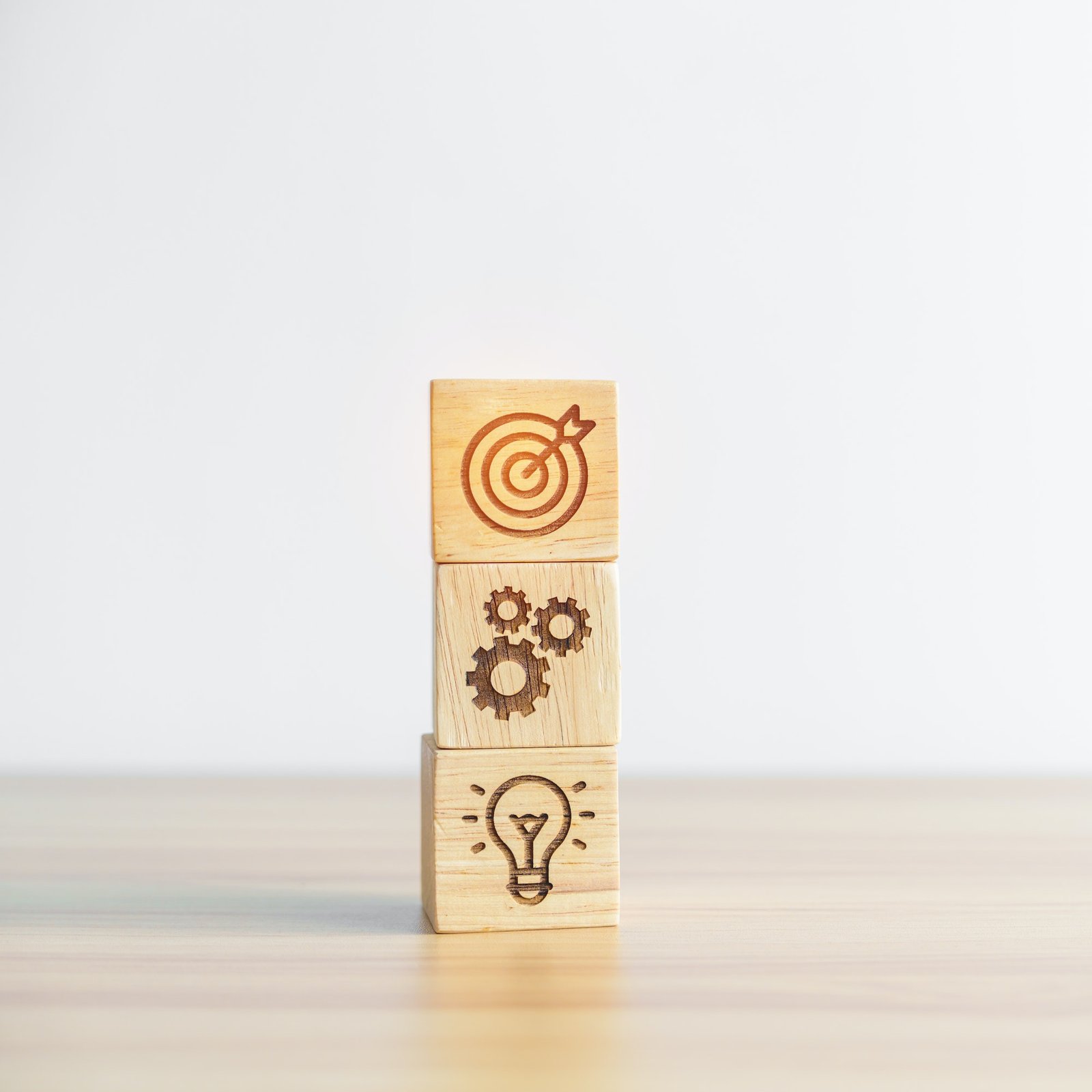 dartboard above Gear and Lightbulb icon block on desk.